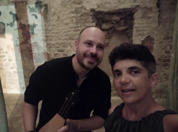 Due musicisti posano con uno strumento ad arco in un interno storico